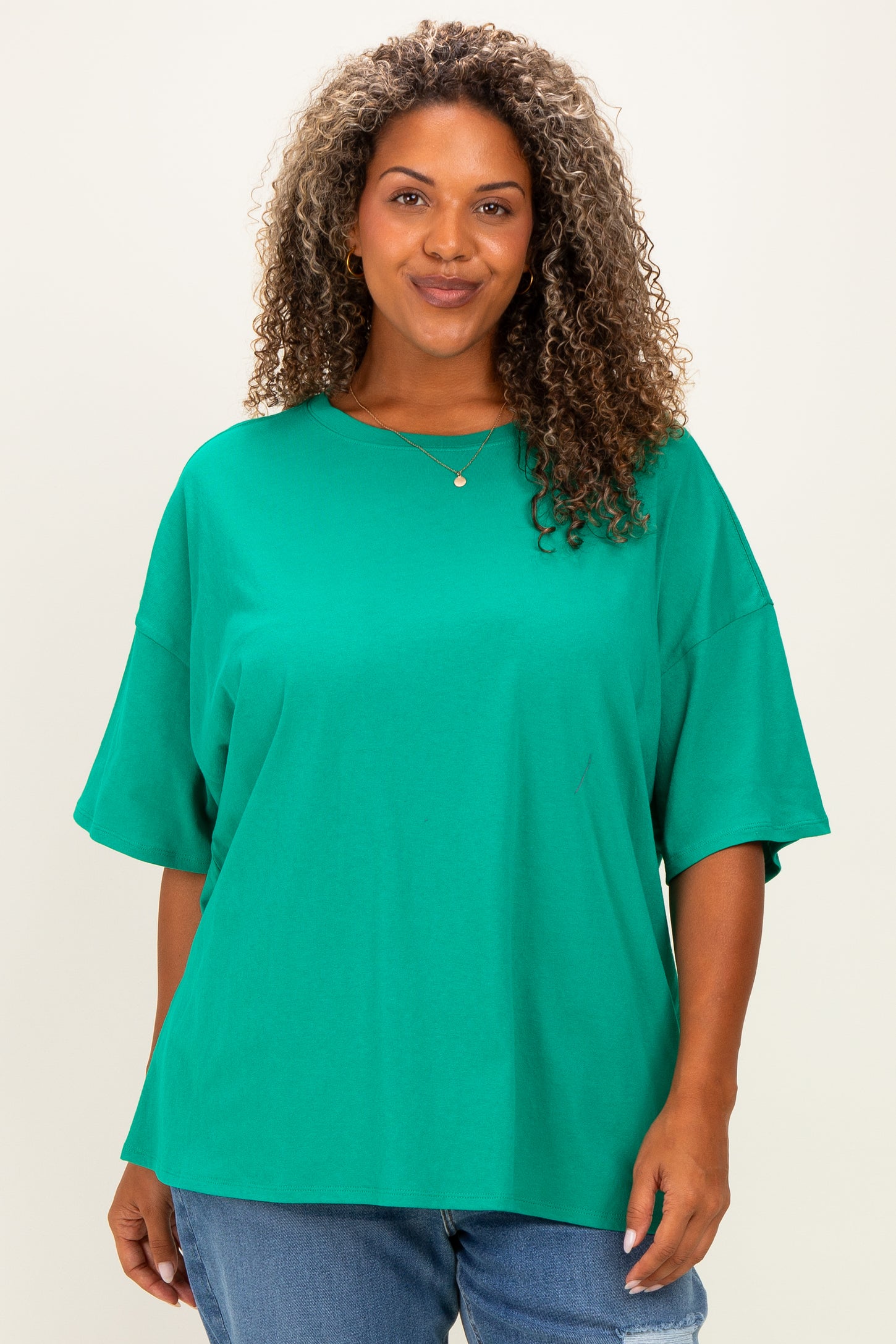 woman wearing a bright green oversized t-shirt with short sleeves and a relaxed fit, smiling at the camera