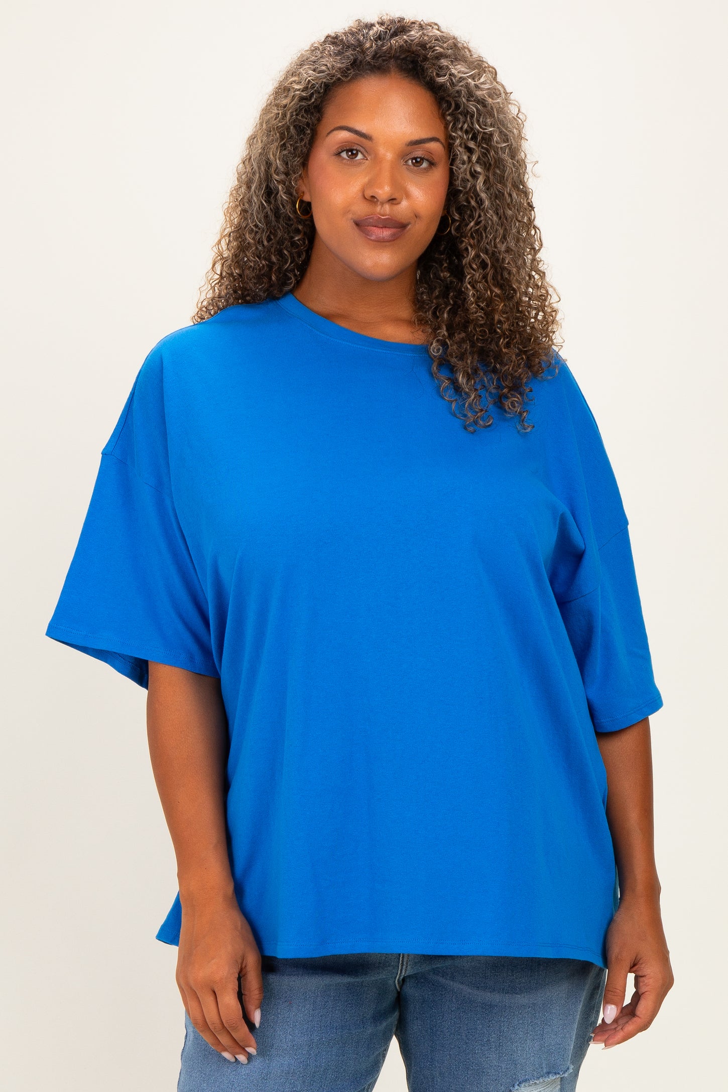 woman wearing a bright blue oversized t-shirt with short sleeves and a relaxed fit, paired with denim jeans