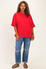 woman wearing a bright red oversized t-shirt and distressed blue jeans with brown sandals