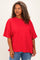 woman wearing a bright red oversized t-shirt with short sleeves and a relaxed fit, paired with denim jeans
