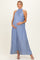 woman wearing a light blue halter neck maternity dress, standing and cradling her baby bump