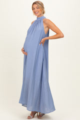 woman wearing a light blue maternity maxi dress with a high neckline and holding her baby bump