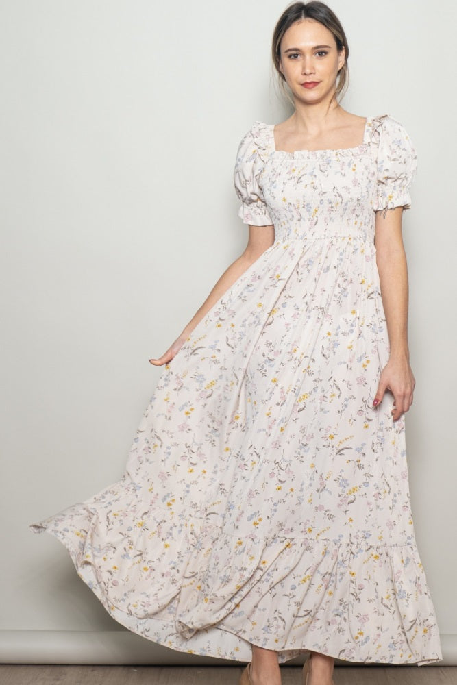 woman wearing a light pink floral maxi dress with puff sleeves and a fitted bodice