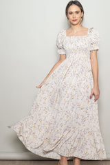 woman wearing a light pink floral maxi dress with puff sleeves and a fitted bodice