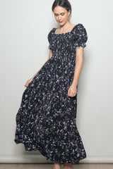 woman wearing a navy floral maxi dress with puff sleeves and a fitted bodice