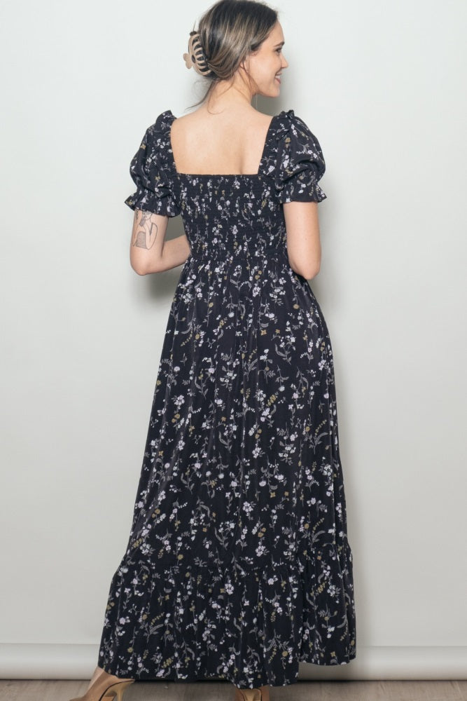 woman wearing a black floral maxi dress with puff sleeves and a smocked back, shown from the back