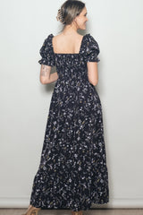 woman wearing a black floral maxi dress with puff sleeves and a smocked back, shown from the back