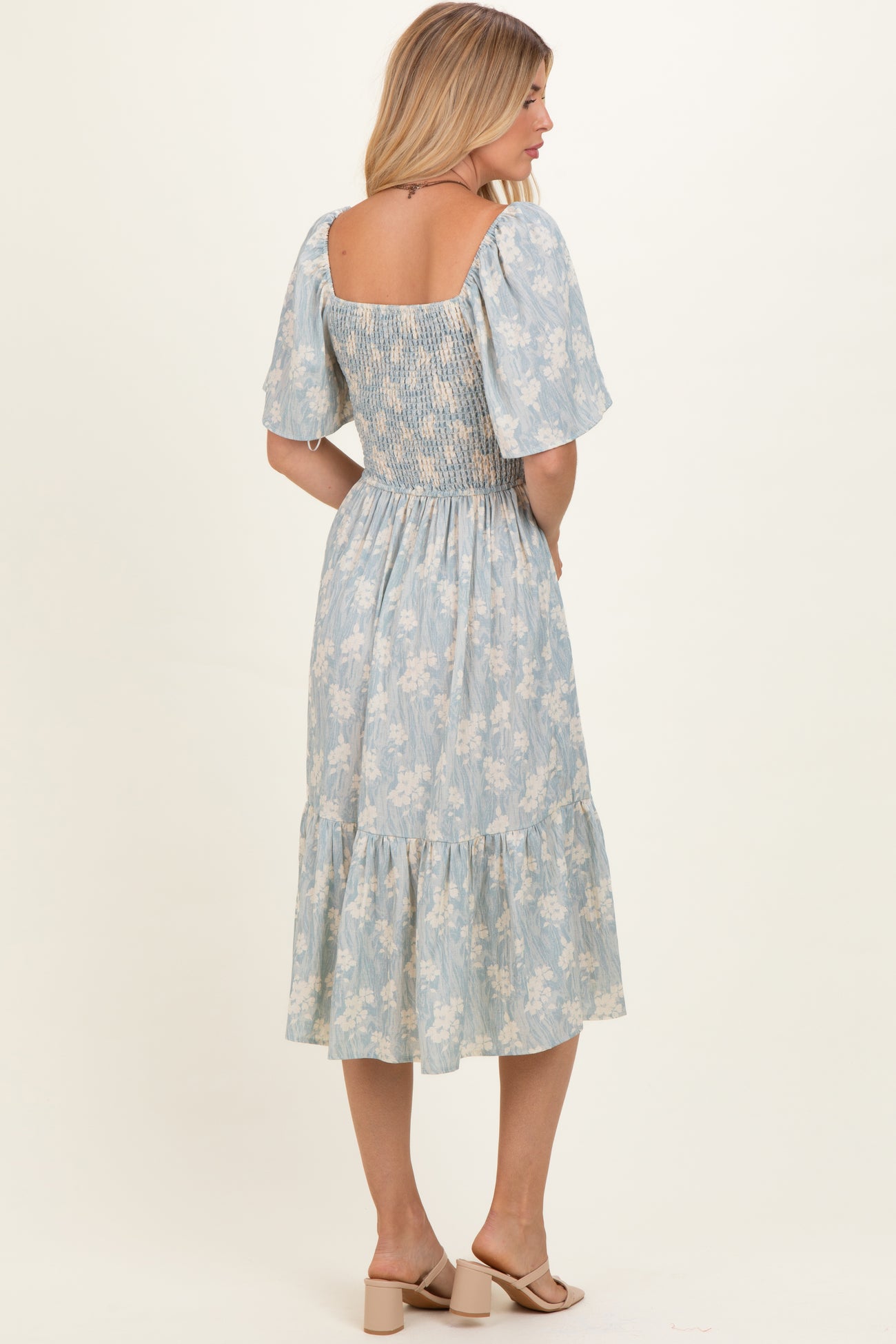 woman wearing a light blue floral midi dress with a smocked bodice and puff sleeves, shown from the back