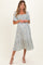 woman wearing a light blue floral maternity dress with short puff sleeves and a tiered skirt, baby bump visible