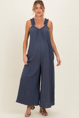woman wearing a navy blue maternity jumpsuit with ruffled straps and wide-leg design, showcasing her baby bump