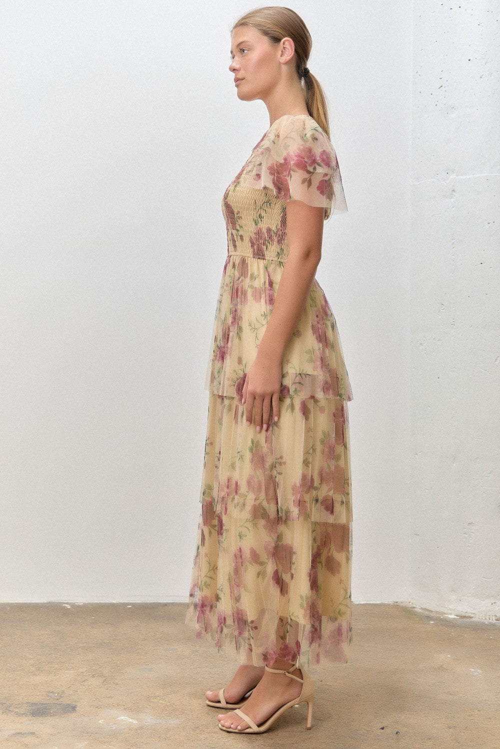 woman wearing a tiered floral print maxi dress in beige with short sleeves and a fitted bodice