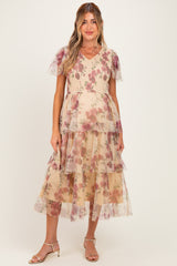 woman wearing a floral tiered maternity dress with short sheer sleeves and a v-neckline, showing a baby bump