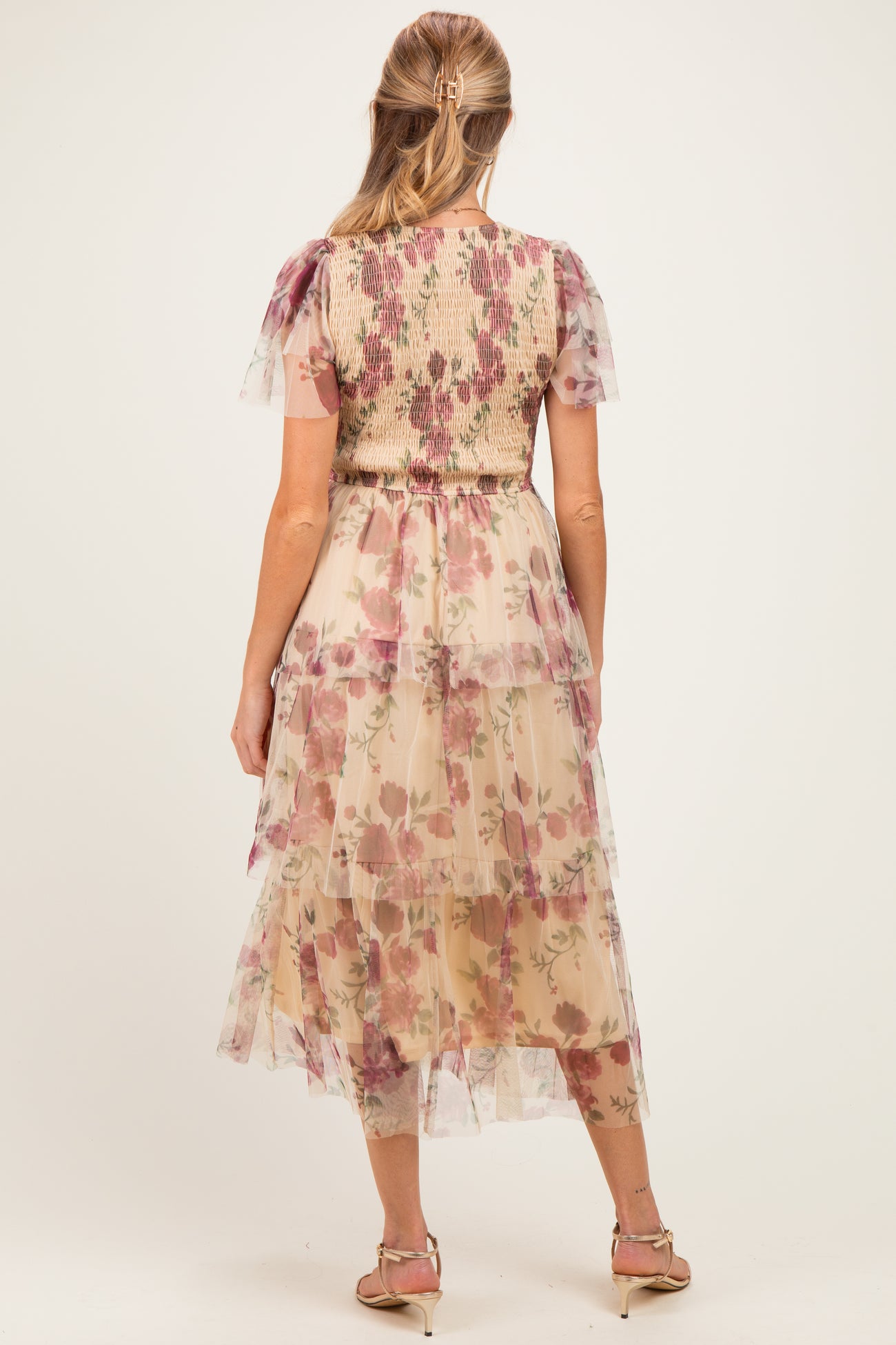 woman wearing a floral tiered maternity dress with short sleeves and a smocked bodice, showing a baby bump from the back