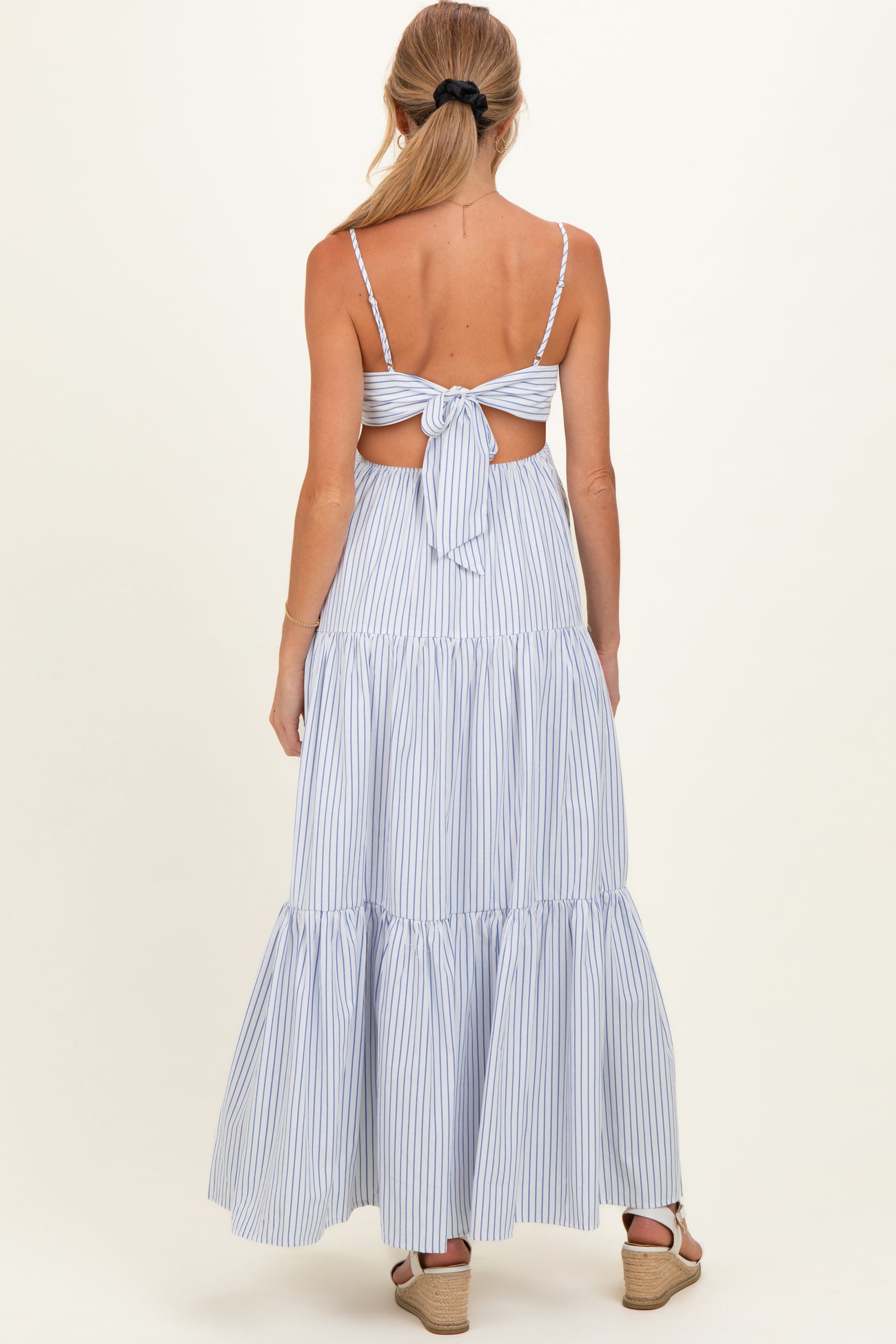 woman wearing a blue and white striped maternity maxi dress with a back tie detail and tiered skirt