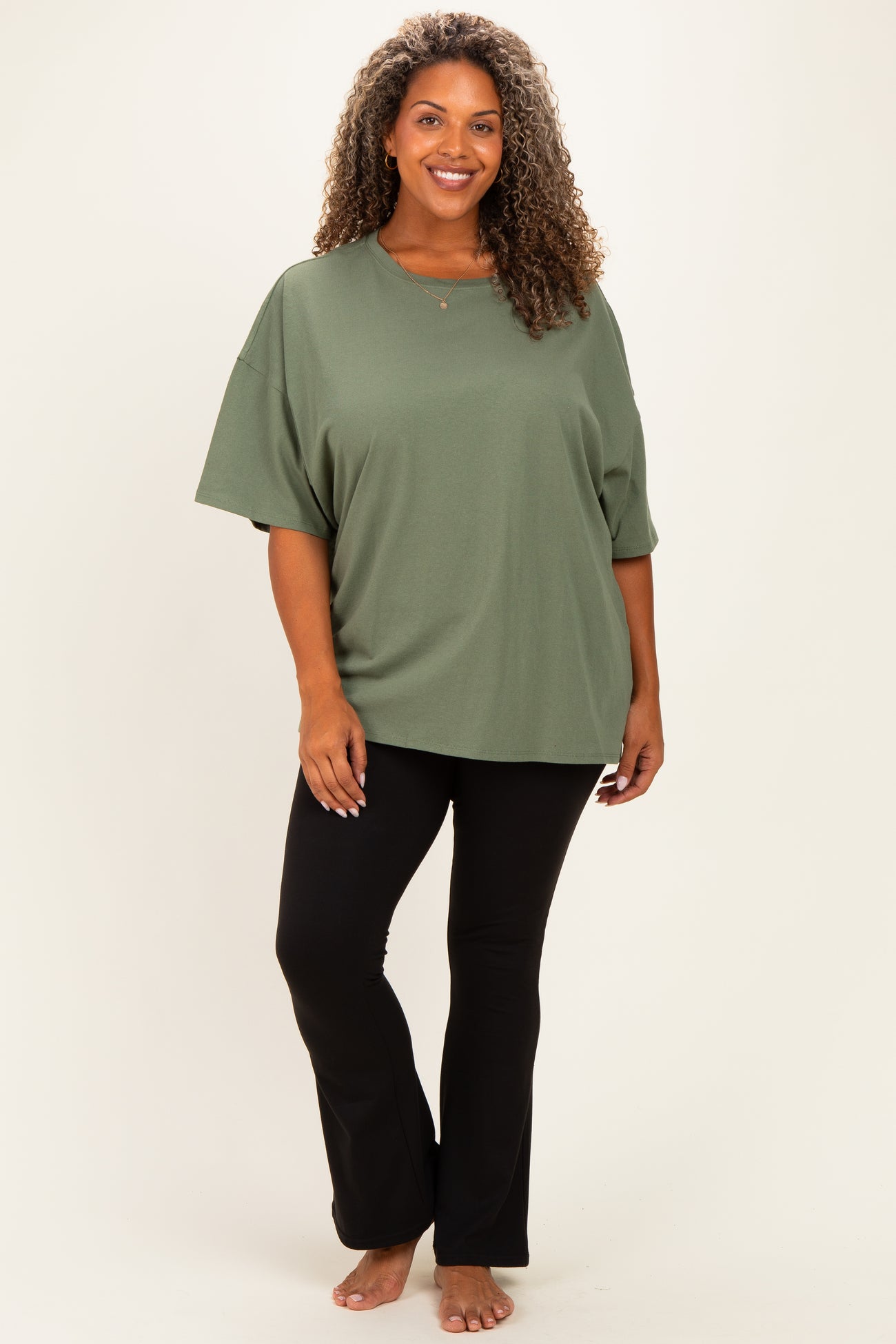 woman wearing an olive green oversized t-shirt with short sleeves and black flared pants