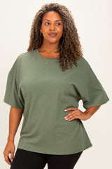 woman wearing a loose-fitting olive green short sleeve top with a relaxed silhouette and black leggings