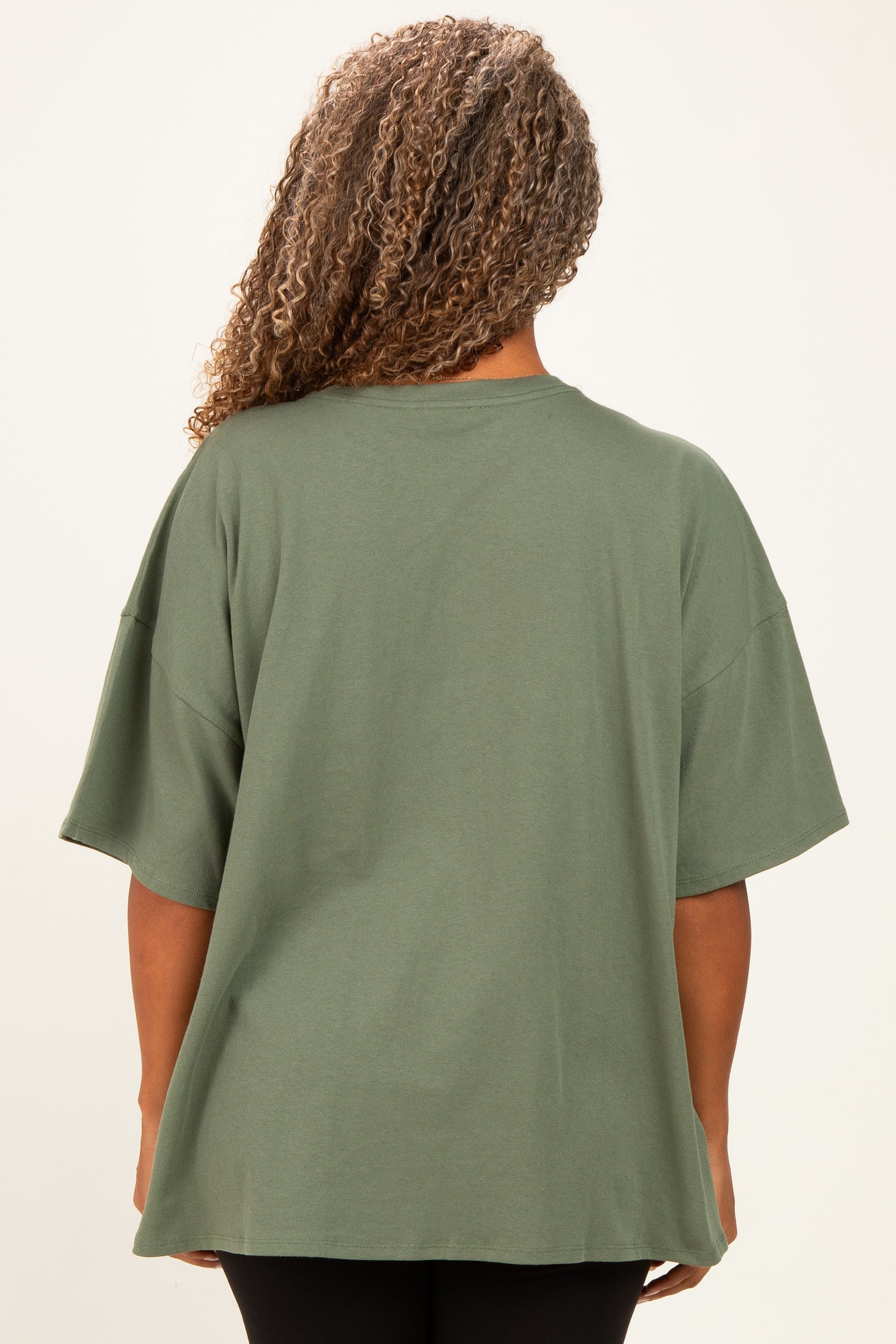 woman wearing a green oversized t-shirt with short sleeves, seen from the back