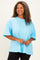 woman wearing a light blue oversized t-shirt with short sleeves, smiling and posing casually