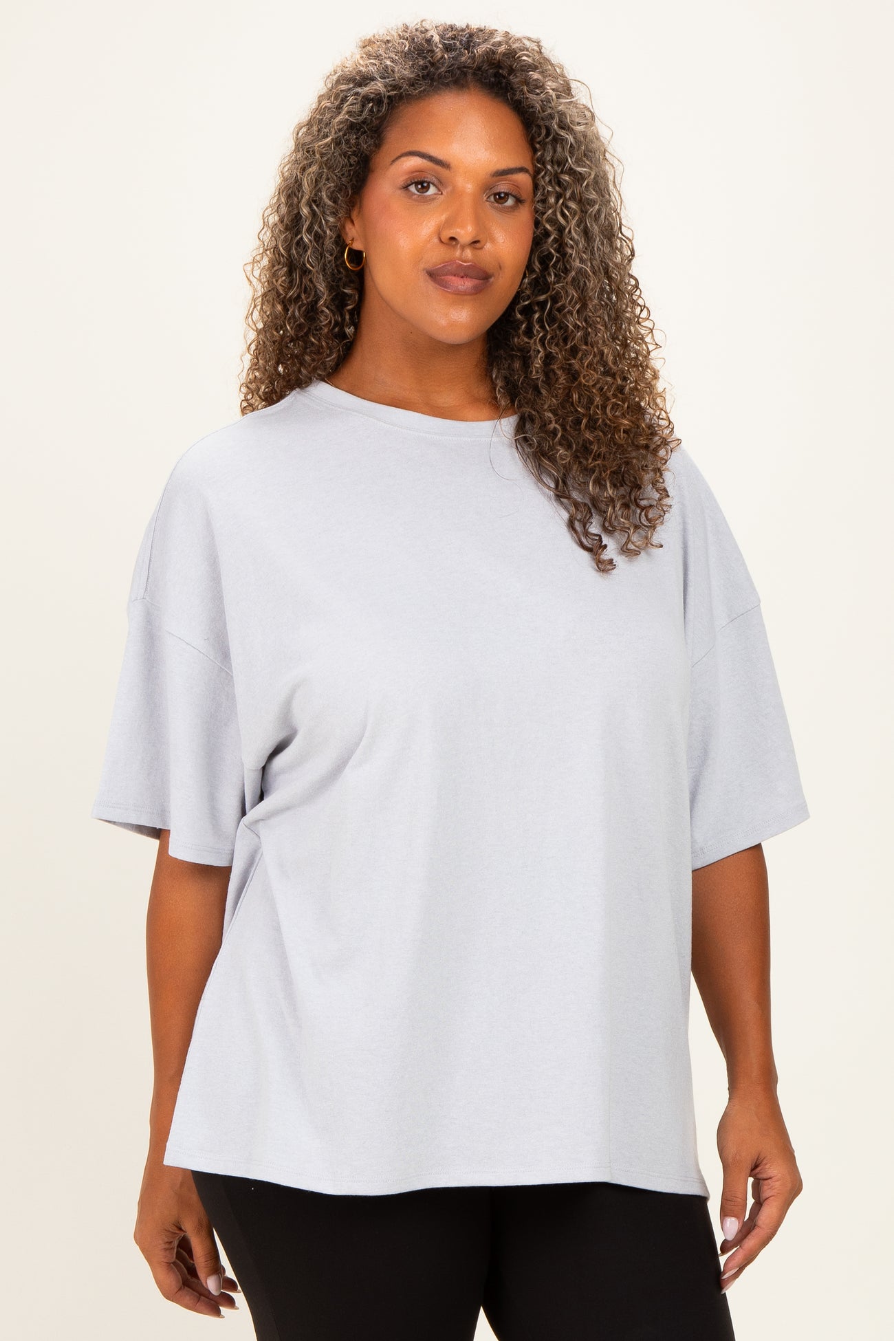 woman wearing a loose-fitting light grey oversized t-shirt with short sleeves and rounded neckline