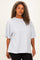 woman wearing a loose-fitting light grey oversized t-shirt with short sleeves and rounded neckline