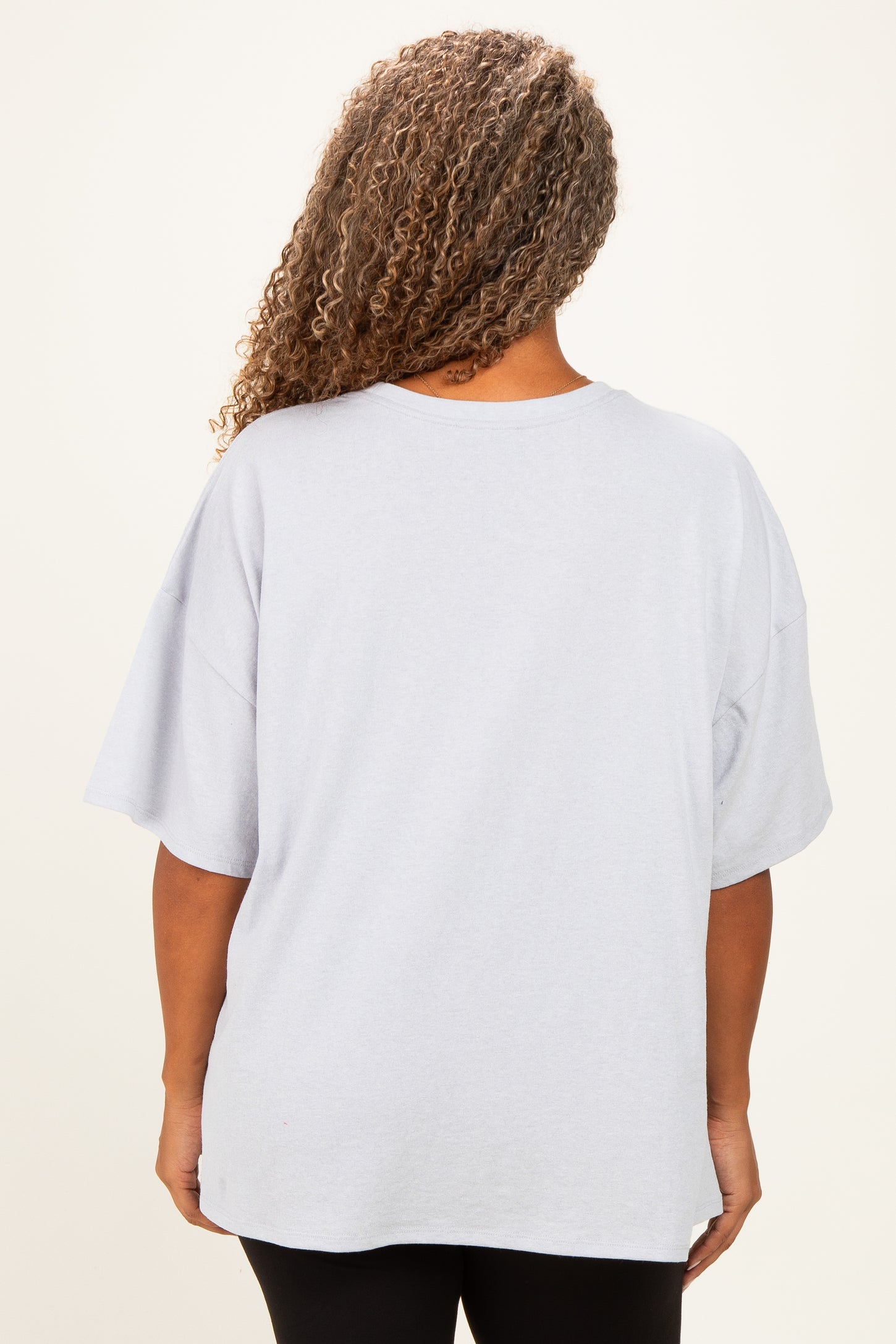 plus size woman wearing a loose-fitting light gray oversized t-shirt, view from the back