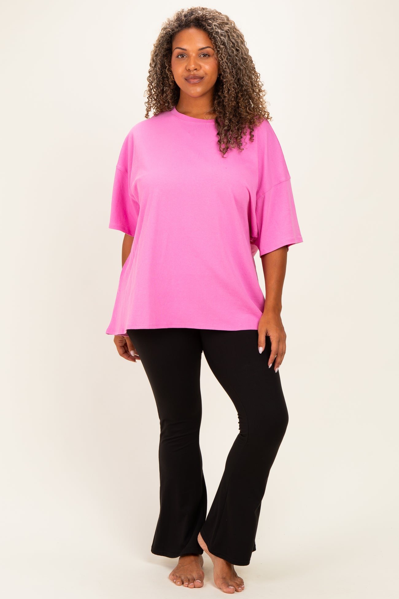 woman wearing a bright pink oversized t-shirt and black flared leggings