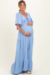 woman wearing a light blue maternity maxi dress with short flutter sleeves and holding her baby bump