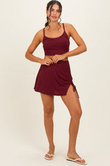 woman wearing a burgundy ribbed sports bra and matching short skirt with side drawstring details