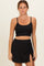 woman wearing a black ribbed maternity crop top and matching skirt with side ruching