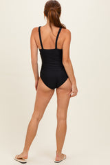 woman wearing a black one-piece swimsuit, showing the back view with adjustable straps and a modest cut