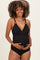 woman wearing a black ribbed maternity swimsuit and holding her baby bump