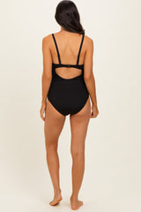 woman wearing a black ribbed one-piece swimsuit with a cut-out back detail