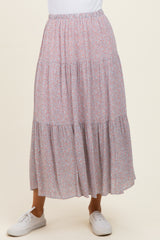 woman wearing a light pink floral tiered maxi skirt with an elastic waistband and white sneakers