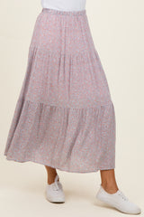 woman wearing a floral patterned maxi skirt with a tiered design and elastic waistband, paired with white sneakers