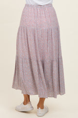 woman wearing a flowy pink floral tiered maxi skirt viewed from the back with an elastic waistband