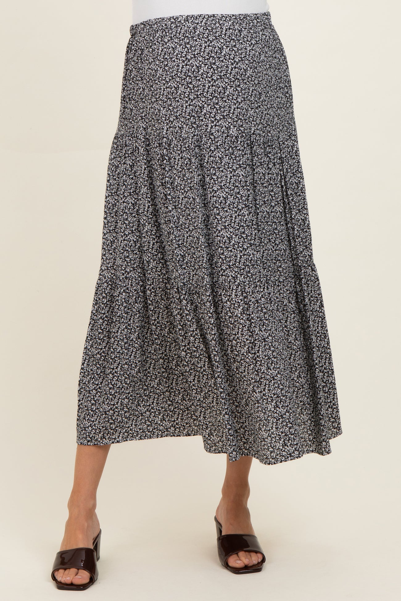 woman wearing a black and white floral print maternity maxi skirt with tiered details and a relaxed fit