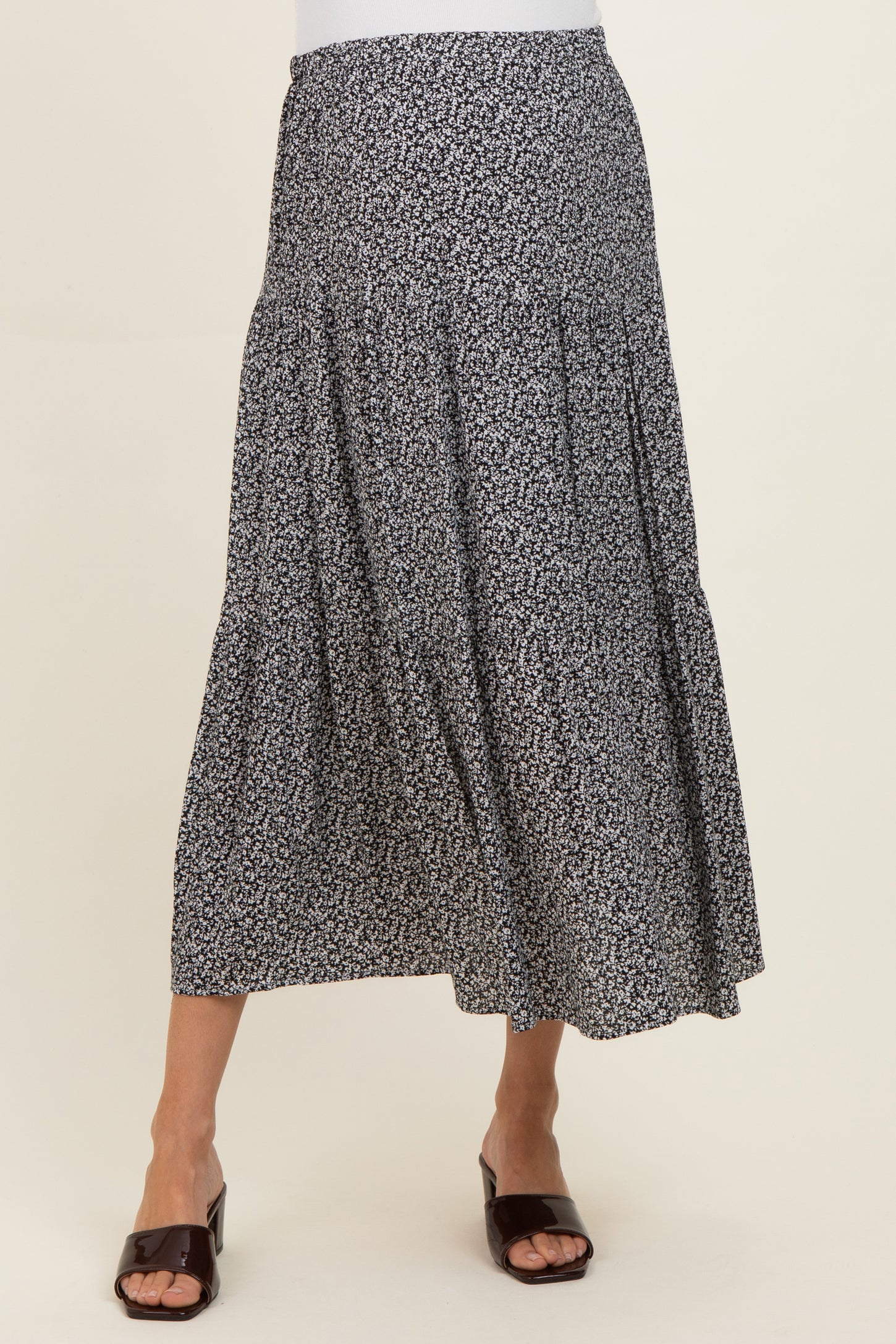 woman wearing a black and white floral print maternity maxi skirt with tiered details and a relaxed fit