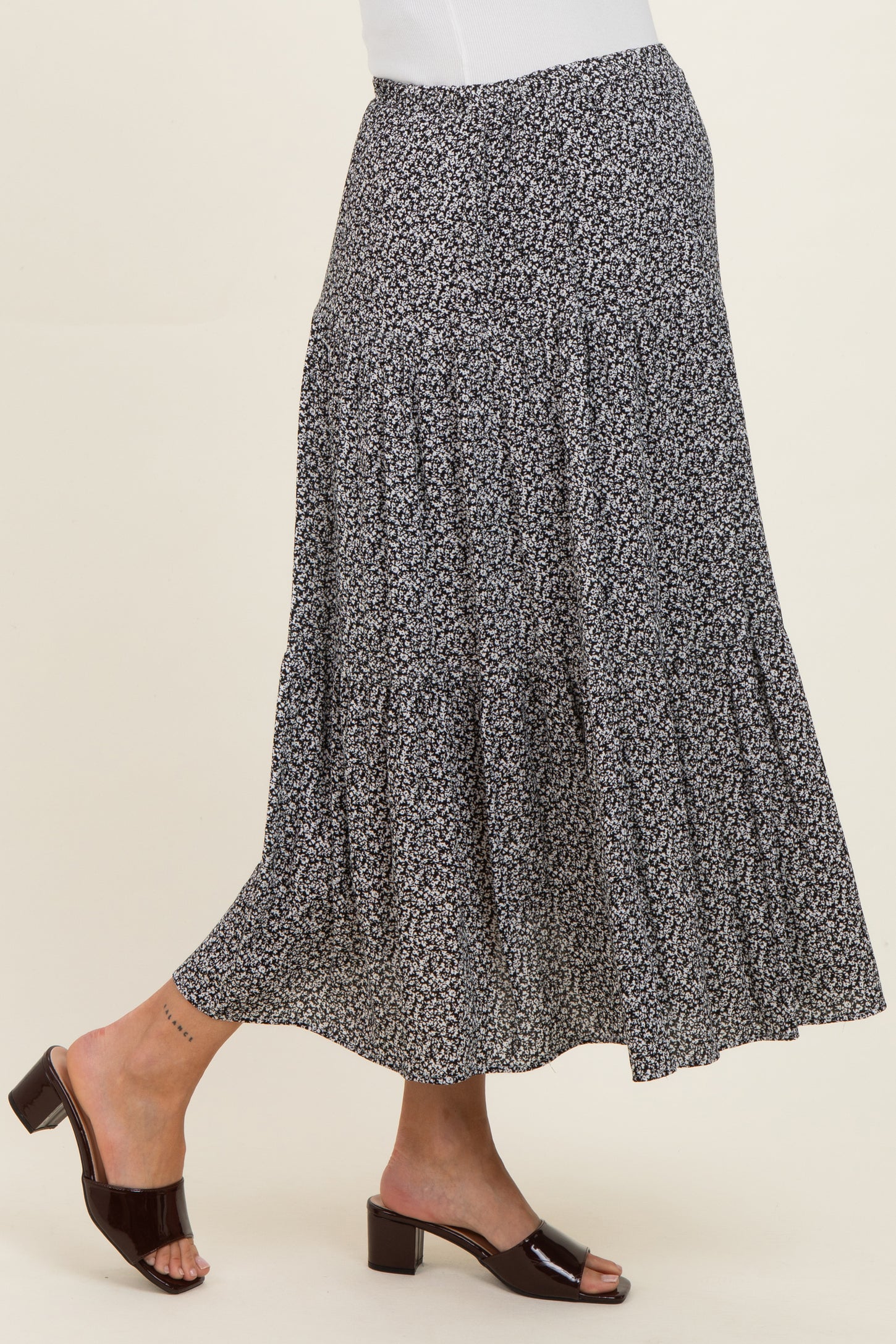 woman wearing a black and white floral print maternity maxi skirt with a flowy design and heeled sandals
