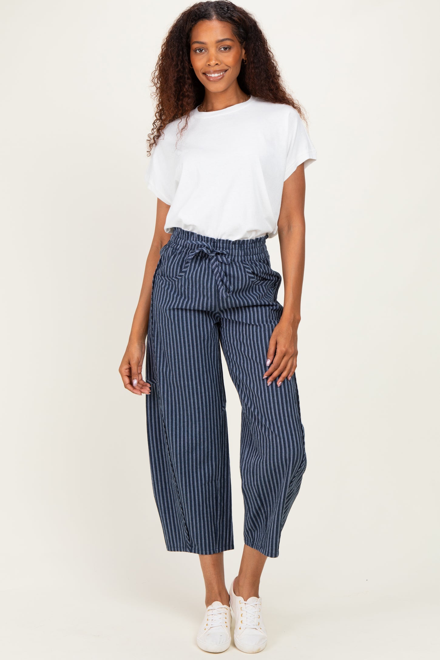woman wearing a white t-shirt and navy striped wide-leg pants with a drawstring waist and white sneakers