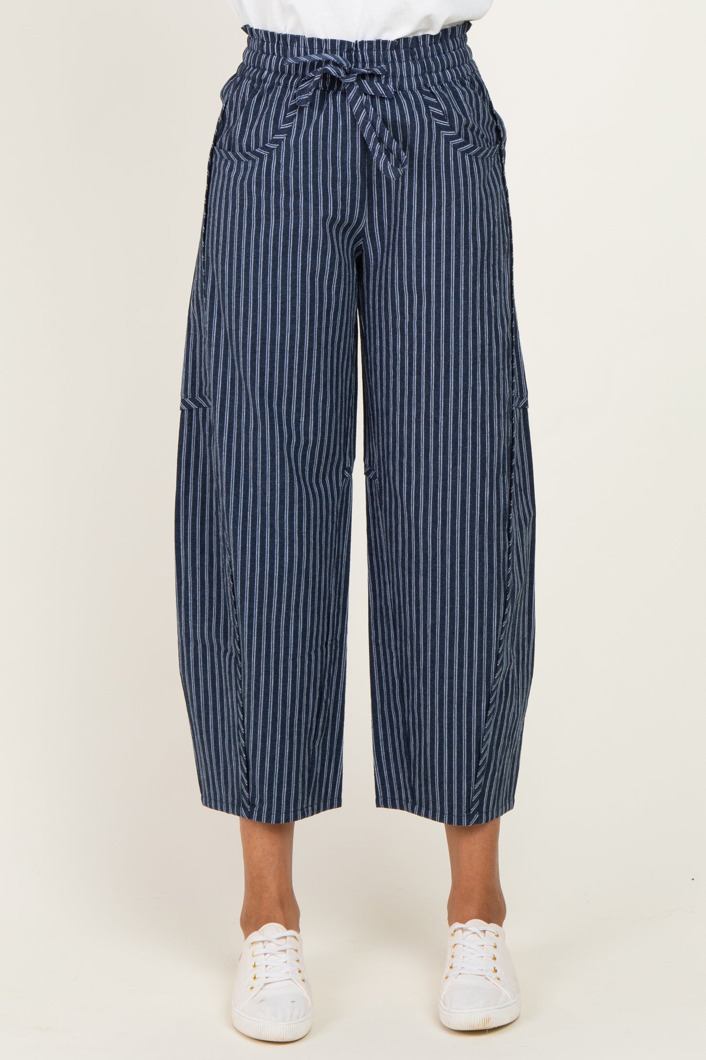 woman wearing navy blue striped wide-leg trousers with a tied waist and side pockets