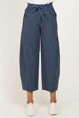 woman wearing navy blue striped wide-leg trousers with a tied waist and side pockets
