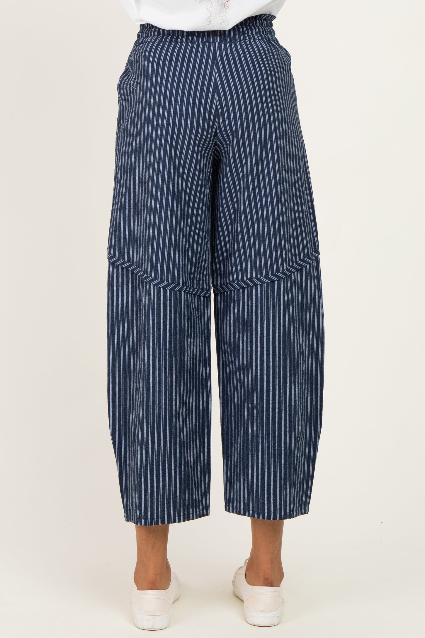 woman wearing navy and white striped wide-leg trousers, shown from the back