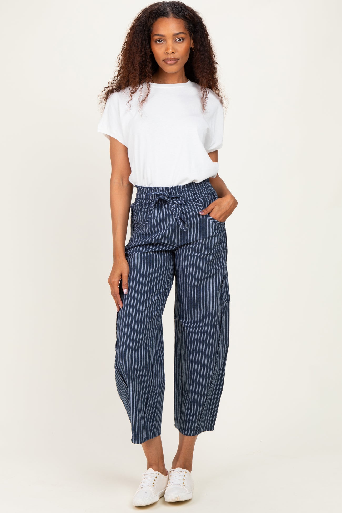 woman wearing a white short sleeve t-shirt and navy blue striped paperbag pants