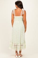 woman wearing a floral patterned maternity maxi dress with lace details and tie straps, showing her baby bump