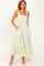 woman wearing a green and white patterned maxi dress with lace straps and pockets