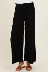 woman wearing black wide-leg maternity pants with a stretchy waistband and sandals