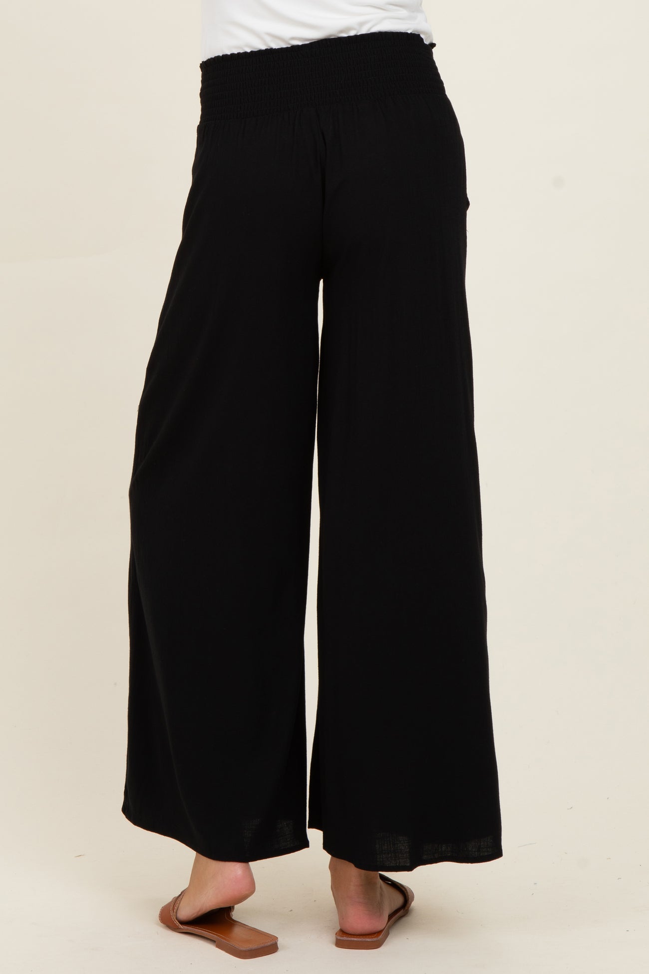 woman wearing black wide-leg maternity pants with a smocked waistband, seen from the back