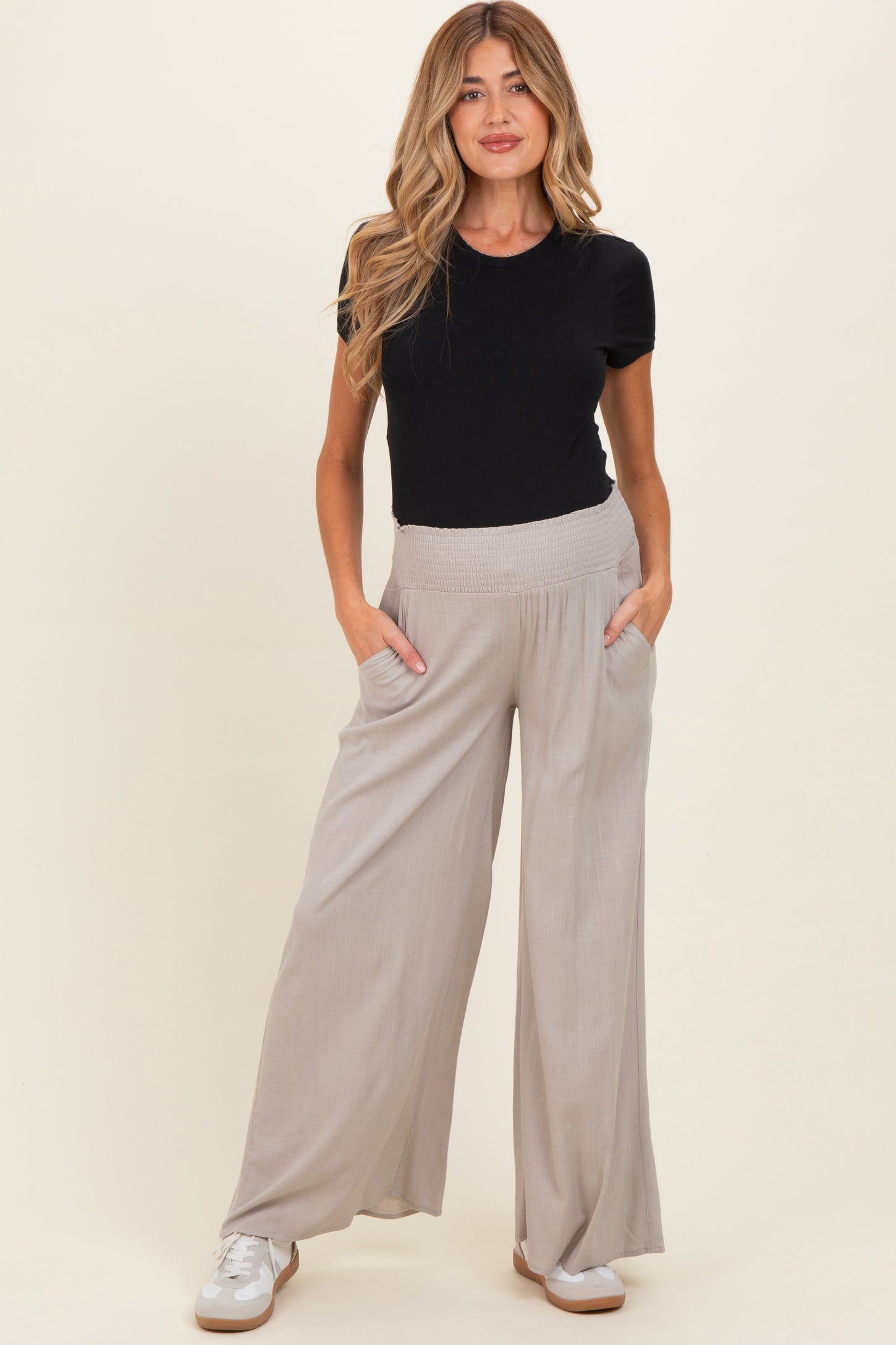 woman wearing a black short sleeve top and light gray wide leg maternity pants with pockets