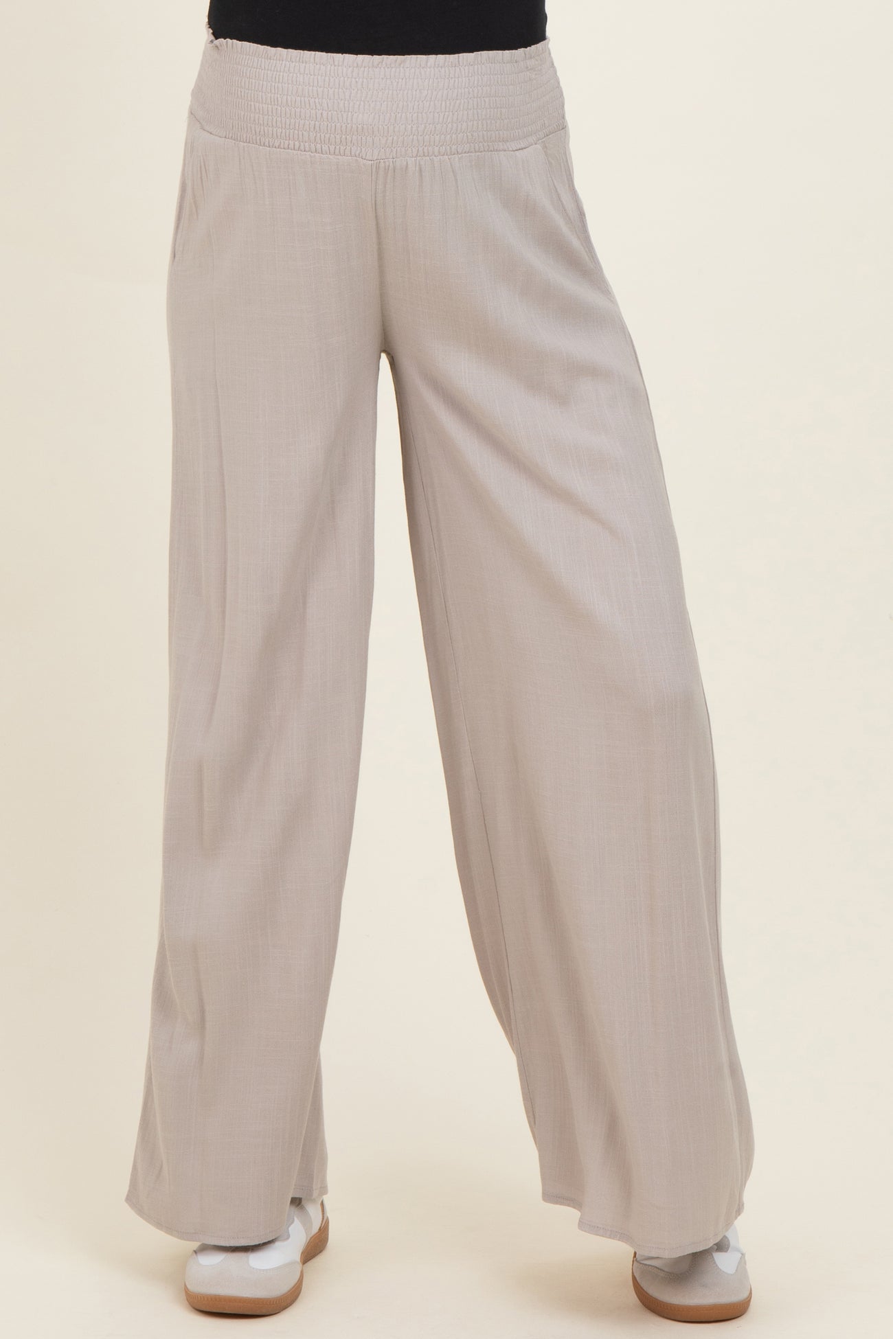 woman wearing light beige maternity wide-leg pants with a smocked waistband