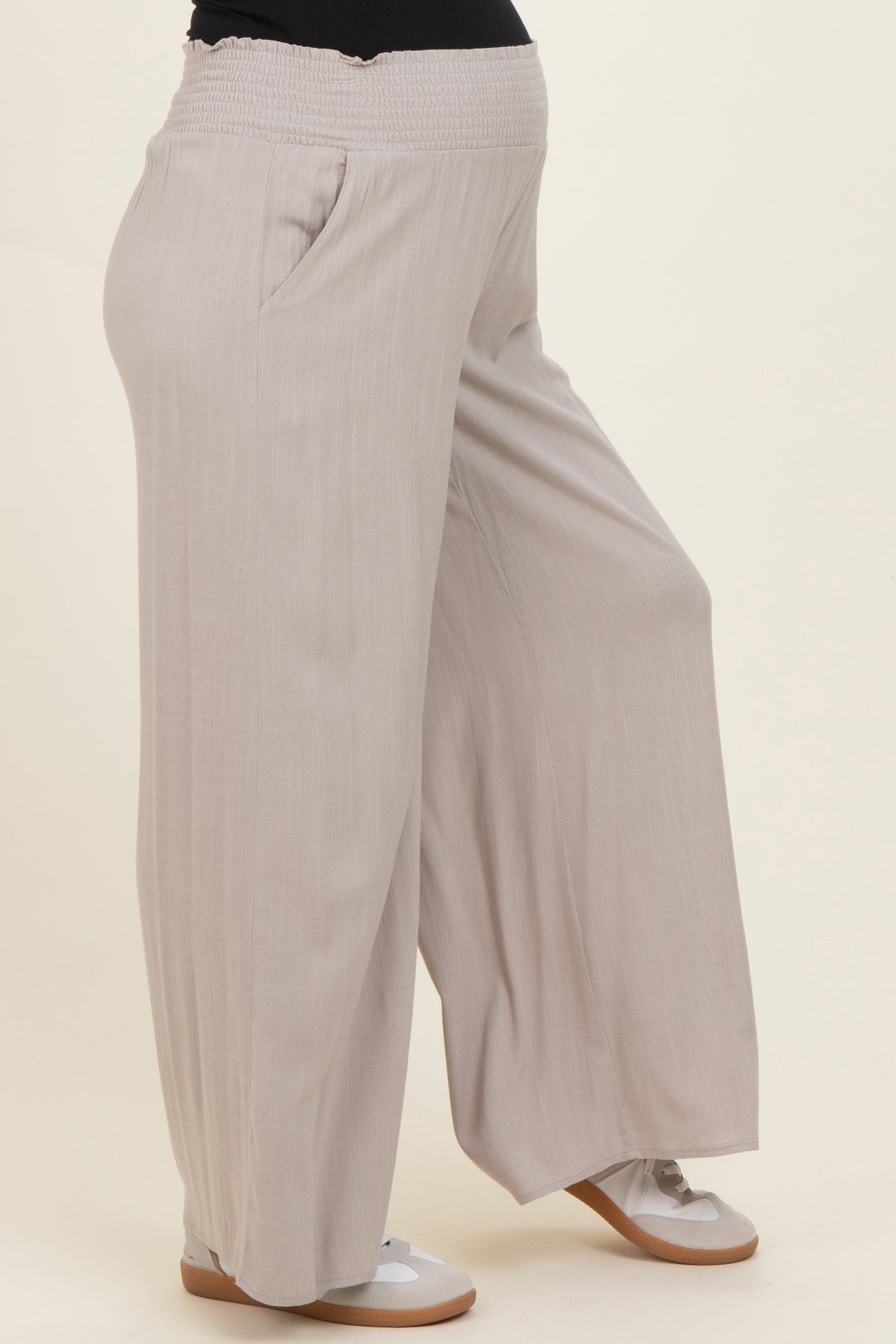 maternity wear light beige wide-leg pants with an elastic waistband and side pockets, worn by a model with a baby bump